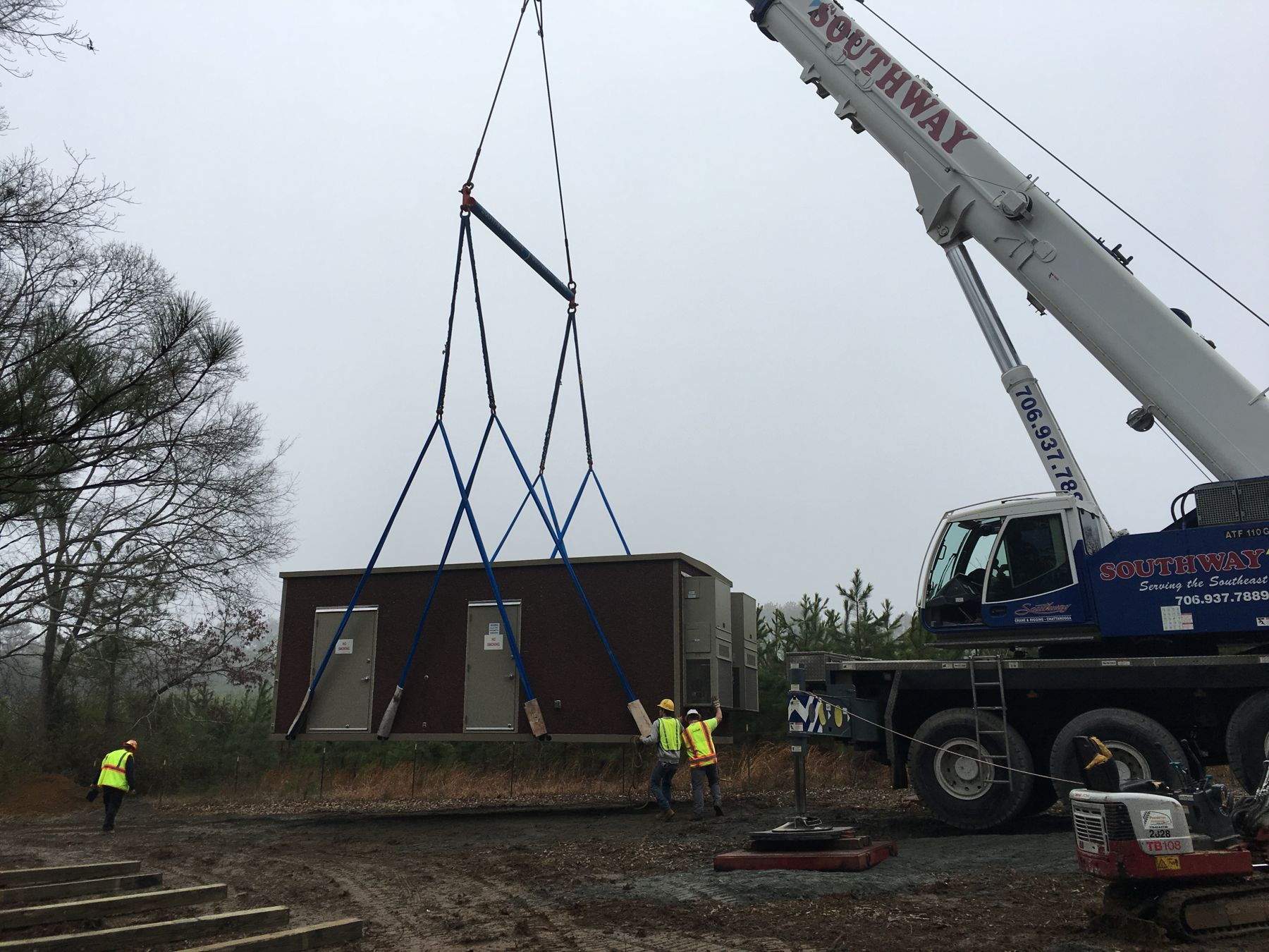 Tesa crew setting an equipment shelter with a crane